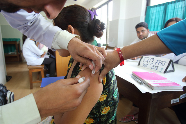 Sabina Rai receives a vaccination from Health Worker Jiban Poudel at the temporary Batulechaur Health Post, Pokhara, Nepal (Flickr/AusAID/Jim Holmes CC BY 2.0)