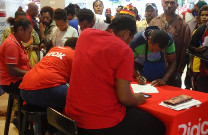 Digicel staff members register customers at a temporary stand while others wait, Port Moresby, December 2017 (Credit: Amanda H A Watson)
