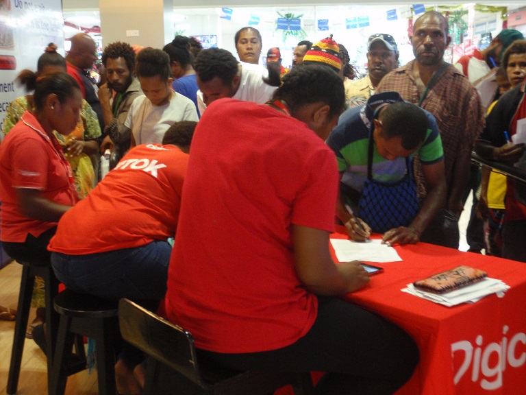 Digicel staff members register customers at a temporary stand while others wait, Port Moresby, December 2017 (Credit: Amanda H A Watson)