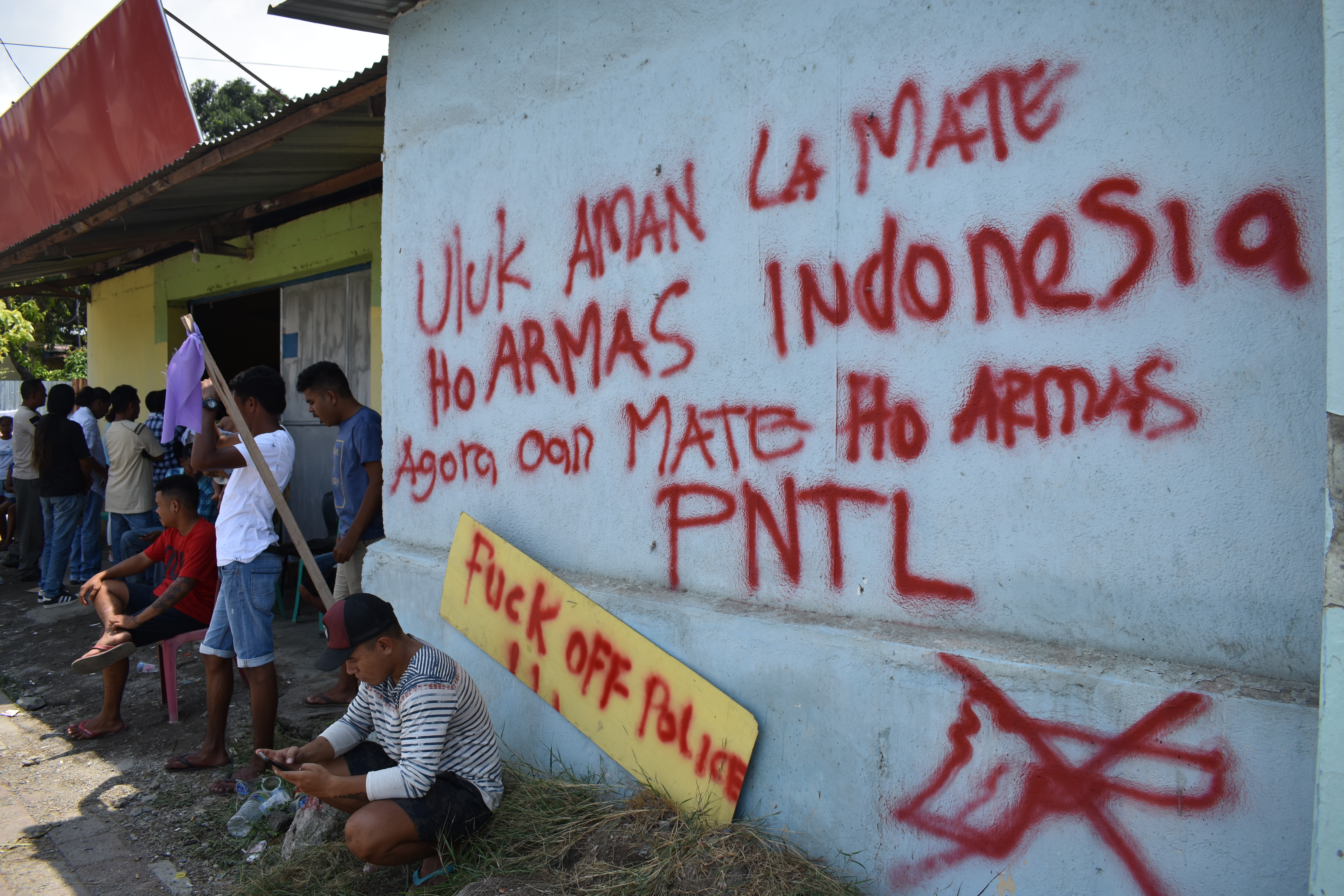 Young men hold vigil outside the homes of the victims' families, in front of anti-police graffiti that now covers the neighbourhood (Photo: Bardia Rahmani)