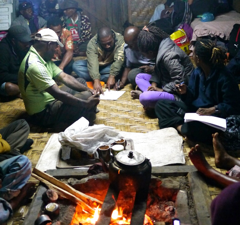 Community development workers from CARE PNG and the Community Development Agency (nightly debrief and reviewing plans during drought response, Gumine District, 2016)