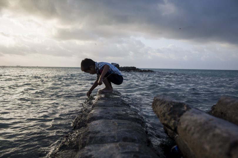 A boy plays on a flooded sea wall in Kiribati (Conor Ashleigh-World Bank)