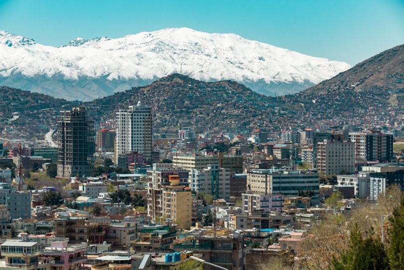 View of the city of Kabul with high rise buildings and snow-capped mountains in the distance.