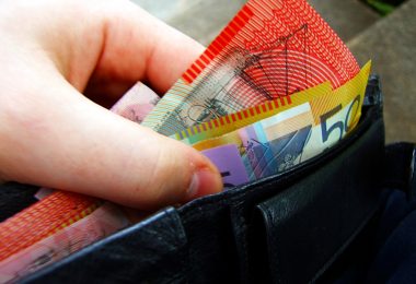 A hand removing Australian banknotes from a wallet