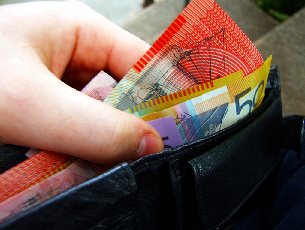 A hand removing Australian banknotes from a wallet