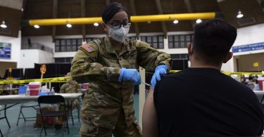 A US infantry officer administers a COVID-19 vaccine in Guam