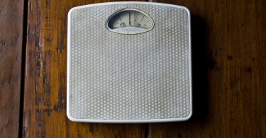 Close up photo of old bathroom scale on wooden floor