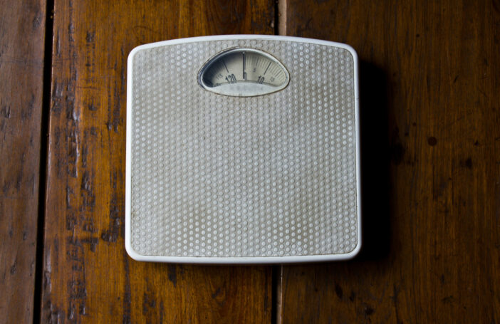 Close up photo of old bathroom scale on wooden floor