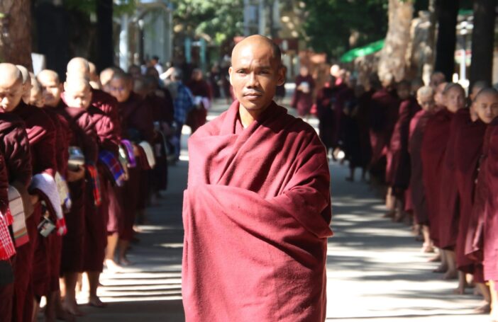 A group of buddhist monks in maroon robes walking